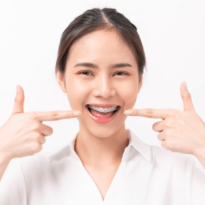 Traditional braces: pros and cons 3 Young woman smiling and pointing toward her traditional braces