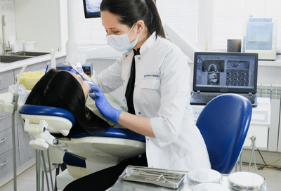 History of orthodontics: how treatment has changed over the years 10 A woman in a white coat and mask working on a patient, representing the history of orthodontics