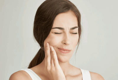 How orthodontic bite correction can improve your bite and reduce jaw strain 12 Woman holding her jaw in pain, representing orthodontic bite correction