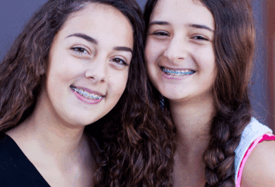 Your first week with braces: what to expect 8 Two girls with braces smiling, representing first week with braces
