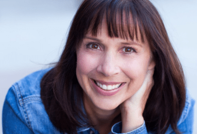 Woman in denim jacket, thoughtful pose, representing link between orthodontics and gum health