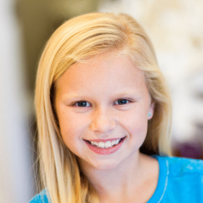 What is the best age for kids to get braces? 3 Little girl with blonde hair smiling at eberle orthodontics, representing best age for kids to get braces